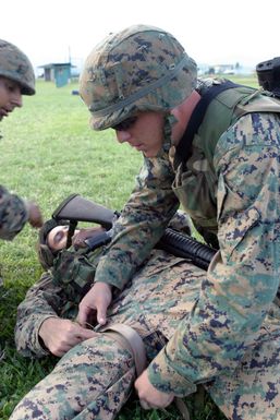 US Marine Corps (USMC) Lance Corporal (LCPL) Martinez, Golf Company, 2nd Battalion (BN) 3rd Marine Regiment, pretends to apply a tourniquet during Squad Competitions in preparation for the Super Squad Competition