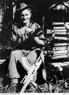 KARAWOP AREA, NEW GUINEA. 1945-04-20. PRIVATE W.H. BARTHOLOMEW, 2/1 INFANTRY BATTALION, OUTSIDE A JAPANESE HUT CAPTURED BY HIS COMPANY. THIS SOLDIER HAS BEEN AWARDED THE MM