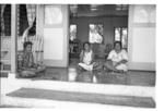 Group portrait, three women seated at front door