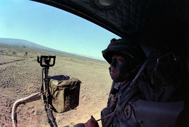 A member of the 1ST Bn., 35th Inf., 25th Inf. Div., looks out from inside a UH-1A Iroquois helicopter as an air-mobile assault takes place during Opportune Journey 4-83