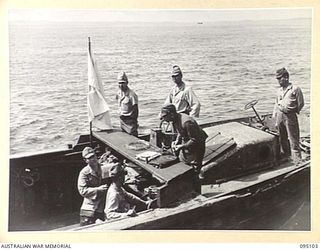 AT SEA, OFF BUIN, BOUGAINVILLE, 1945-08-20. A JAPANESE MEMBER OF SURRENDER ENVOY PARTY PASSING ON PROGRESS RESULTS TO DRIVER OF BARGE DURING SURRENDER NEGOTIATIONS ON BOARD THE CORVETTE HMAS ..