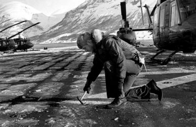 Aviation Electronics Technician 3rd Class Randy Dowdy chips ice from a padeye on the flight deck of the amphibious assault ship USS GUAM (LPH-9). The ship is participating in the NATO exercise Cold Water (COLDEX-FLOTEX '81). The exercise is intended to test all phases of amphibious operations in sub-freezing weather