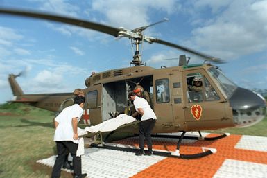 Hospital personnel and US Army medics from the 68th Medical Detachment, 25th Infantry Division, place a patient into a UH-1 Iroquois helicopter for a flight to a hospital in Honolulu