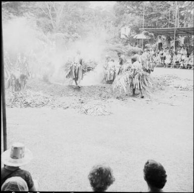 Fijian men, dressed in traditional costumes, placing bundles of leaves on the fire, Fiji, 1966 / Michael Terry