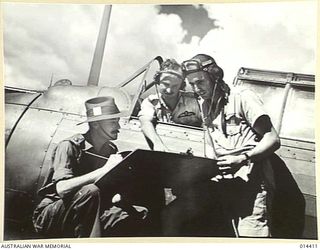 1943-03-10. NEW GUINEA. SELECTING POSSIBLE TARGETS FROM A MAP. AN ARMY OFFICER, F/O J.R. MOWBRAY (WHO WON THE SILVER STAR AT BUNA) AND SGT. P. LAMB (OBSERVER) AT AN OPERATIONAL BASE IN NEW GUINEA