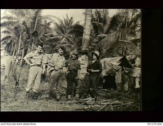 Milne Bay, New Guinea. 1942-07. Four members of No. 30 Squadron RAAF beside their tents in a camp amongst palm trees. Left to right: Flying Officer Douglas G. Raffen (pilot), Sergeant (Sgt) Harold ..