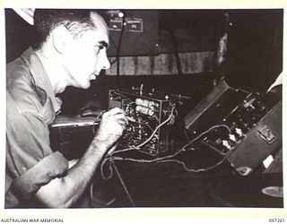 CAPE WOM, NEW GUINEA. 1945-09-29. SIGNALMAN K. WELLS MAKING A ROUTINE CHECK OF A MODULATOR UNIT AT RADIO 6 DIVISION, HEADQUARTERS 6 DIVISION. THE STATION REOPENED ON 6 SEPTEMBER 1945