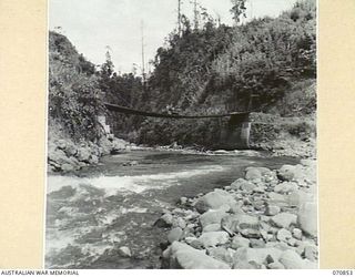 WAU - LAE ROAD, NEW GUINEA, 1944-02-20. A SUSPENSION BRIDGE BUILT BY AUSTRALIAN ARMY ENGINEERS ACROSS THE BULOLO RIVER SIX AND A HALF MILES FROM WAU. IT REPLACES A BRIDGE DESTROYED BY AUSTRALIAN ..
