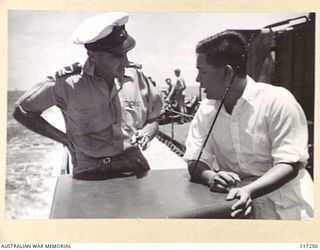 Lieutenant G H Lording, Intelligence Officer RAN questioning Nai Fai Ma, a Chinese interpreter, aboard HMAS Diamantina prior to the Japanese surrender ceremony