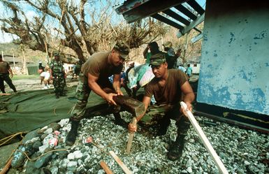 Jose Saifoloi and PFC Lagai Malologa, 100th Battalion, 42nd Infantry Division, American Samoa, pound in stakes for tents being erected for islanders who lost their homes when Cyclone Val struck the South Pacific island of American Samoa