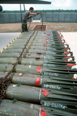 AIRMAN 1ST Class Ron Diego, a munitions specialist with the 43rd Bomb Wing, removes a chain from a row of Mark 82 500-pound bombs during exercise Giant Warrior '89