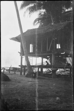 Man sitting on a platform beneath a house, New Guinea, ca. 1929 / Sarah Chinnery