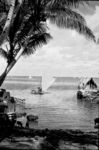 Laden outrigger approaching lagoon shore of village.