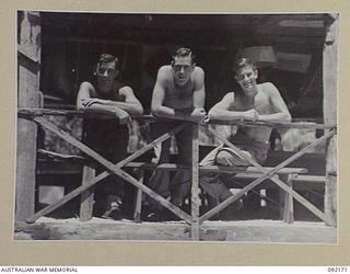 JACQUINOT BAY, NEW BRITAIN. 1945-05-18. MEN OF HEADQUARTERS 5 DIVISION LEANING OVER THE RAIL OF THEIR MESS HUT WATCHING THE SEA. IDENTIFIED PERSONNEL ARE:- PRIVATE C.W. YOUNG (1); PRIVATE L. ..