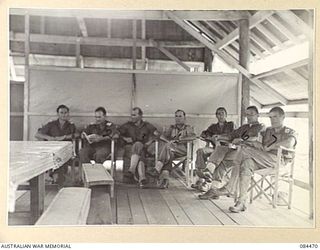 LAE, NEW GUINEA. 1944-12-21. OFFICERS RELAXED IN THE OFFICERS' MESS, 2/3 FORESTRY COY. THE WAR ESTABLISHMENT PROVIDES 6 OFFICERS WITH 2 ATTACHED AND 154 OTHER RANKS. IDENTIFIED PERSONNEL ARE:- ..