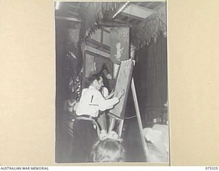 LAE, NEW GUINEA. 1944-08-17. THE LIGHTNING CARTOONIST AT WORK DURING THE CONCERT STAGED BY THE WHITE HORSE INN CONCERT PARTY AT HQ NEW GUINEA FORCE. THE CONCERT PARTY CONSISTS OF MEMBERS OF THE ..