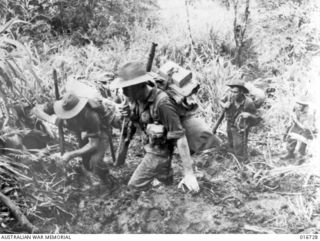 1944-03-23. NEW GUINEA. AUSTRALIANS PLOUGH THROUGH THE MUD DURING A 3000 FEET CLIMB AT CAMERON'S KNOLL IN THE TOUGH FINISTERRE RANGES. THIS UNIT IS MOVING ALONG THE TRACK THAT LEAD TO JAPANESE-HELD ..