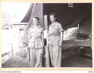 RABAUL AREA, NEW BRITAIN. 1945-09-17. SISTER M.M. WILSON (1) AND SISTER F.E. HENRY (2), STANDING IN FRONT OF THEIR TENT INSIDE A SPECIAL AREA AT 4 FIELD AMBULANCE. THE NURSING SISTERS WERE FLOWN TO ..
