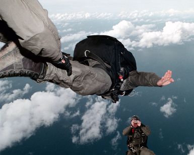 A US Navy (USN) Sailor assigned to Naval Special Warfare Unit One (NSWU1), takes a picture of the other jumpers exiting the ramp of helicopter during a High Altitude Low Opening (HALO) jump over Orote Point, Santa Rita, Guam