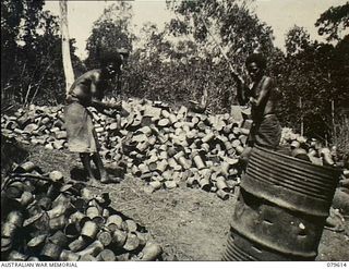 Oro Bay, New Guinea. 1943-04. Tins being crushed by natives and burnt at the incineration area of the 10th Field Ambulance, Army Medical Corps prior to disposal by burial