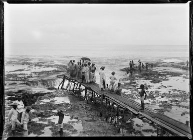 Niueans waiting on a wharf at low tide, during the visit of the HMS Mildura and Lord Ranfurly