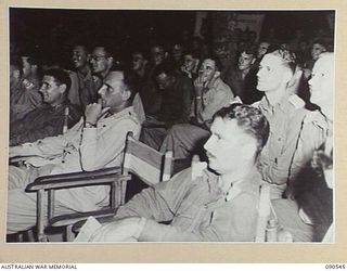 JACQUINOT BAY, NEW BRITAIN. 1945-04-15. AN APPRECIATIVE AUDIENCE WATCHES INTENTLY AS "ABDULLAH THE GREAT" PUTS HIS ACT OF FLOATATION ON IN A CONCERT STAGED BY MEMBERS OF 33 DOCKS OPERATING COMPANY, ..