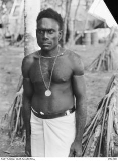 PURIATA RIVER AREA, BOUGAINVILLE. 1945-04-03. MUSIAMO, THE BLACK BRIGADIER AN AUSTRALIAN NEW GUINEA ADMINISTRATIVE UNIT NATIVE WEARING THE LOYAL SERVICE MEDAL PRESENTED TO HIM FOR ORGANISING ..