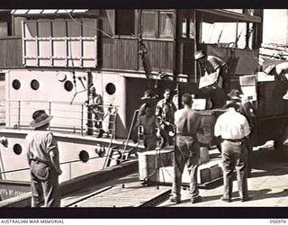 CAIRNS, QLD. 1943-09-07. LOADING CANTEEN GOODS FOR NEW GUINEA. SHOWN: SX8398 PRIVATE S. YENDALL (1) OF THE AUSTRALIAN DEFENCE CANTEENS SERVICE