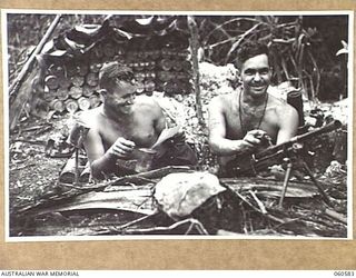 SATTELBERG AREA, NEW GUINEA. 1943-11-15. CHEERFUL BROTHERS, VX47981 CORPORAL L. C. WRIGHT (LEFT) AND VX47996 PRIVATE S. A. WRIGHT BOTH OF MANANGATANG, VIC, (RIGHT) PHOTOGRAPHED IN THEIR MORTAR PIT ..
