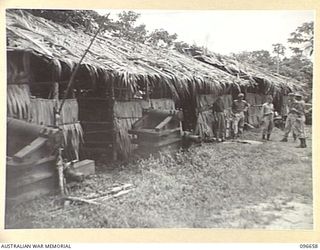 BUKA ISLAND, BOUGAINVILLE AREA. 1945-09-16. MEMBERS OF THE SURRENDER PARTY FROM HEADQUARTERS 2 CORPS TALKING WITH JAPANESE NAVAL PERSONNEL OUTSIDE A JAPANESE STORE WHERE SMALL ARMS AND AMMUNITION ..