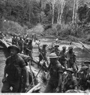 PAPUA, NEW GUINEA. 1942-10. A PATROL OF 2/25TH AND 2/33RD AUSTRALIAN INFANTRY BATTALIONS CROSSING THE BROWN RIVER BY MEANS OF A BRIDGE CONSTRUCTED FROM A FALLEN TREE ON THEIR WAY FORWARD TO MENARI