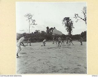 TOROKINA, BOUGAINVILLE ISLAND. 1945-01-13. A HOCKEY MATCH IN PROGRESS BETWEEN TEAMS FROM HEADQUARTERS, 2ND AUSTRALIAN CORPS AND THE ROYAL NEW ZEALAND AIR FORCE ON THE PIVA AIRSTRIP