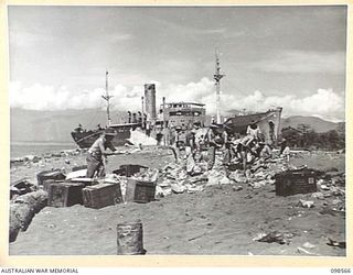 MALAHANG BEACH, LAE, NEW GUINEA. 1945-10-16. TROOPS OF FIRST ARMY DESTROYED SURPLUS AMMUNITION AT MALAHANG BEACH. THEY ARE SHOWN EMPTYING CORDITE FROM CHARGE. THE WRECK OF THE JAPANESE VESSEL, ..