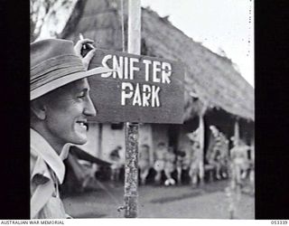 SOGERI VALLEY, NEW GUINEA. 1943-06-25. QX16182 STAFF SERGEANT D. L. MARSHALL STANDING BY THE SIGNBOARD IN FRONT OF THE MAIN WARD OF THE 11TH AUSTRALIAN FIELD AMBULANCE. "SNIFTER PARK" IS THE NAME ..