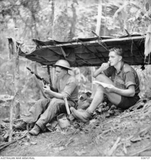 PAPUA. 1942-09. MEN OF THE 2/14TH INFANTRY BATTALION RESTING UNDER A MAKESHIFT SHELTER NEAR THEIR POSITIONS ON A RIDGE OVERLOOKING THE VALLEY LEADING TO IORIBAIWA. HAROLD (DUTCHY) ATKINSON (LEFT) ..