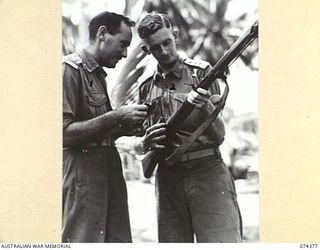 SIAR, NEW GUINEA. 1944-06-27. VX112180 CAPTAIN S.R. HEDLEY, INTELLIGENCE OFFICER (1) AND VX112187 CAPTAIN R.J. BENCHLEY, AUSTRALIAN ELECTRICAL AND MECHANICAL ENGINEERS (2) EXAMINING A NEW TYPE OF ..