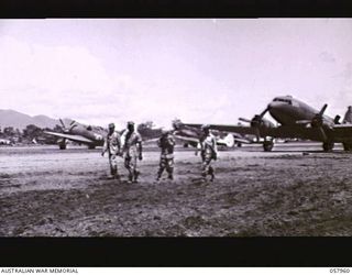 LAE, NEW GUINEA. 1943-10-11. TRANSPORT AND FIGHTER AIRCRAFT LINED UP ON THE AIRSTRIP. THE DOUGLAS IS ON THE RIGHT WITH A THUNDERBOLT AND TWO KITTYHAWKS ON THE LEFT