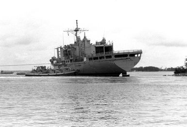 The large harbor tug WEEHAWKEN (YTB-776), foreground, maneuvers the combat stores ship USS WHITE PLAINS (AFS-4) back toward the water after it ran aground at Polaris Point, Apra Harbor. The WHITE PLAINS dragged its anchor across Apra Harbor and ran aground after heavy winds broke the vessel free from its moorings when Typhoon Omar passed through the area on August 28th