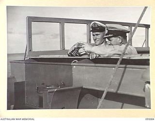 AT SEA, OFF BUIN, BOUGAINVILLE. 1945-08-20. COMMANDER A.E. FOWLER, NAVAL OFFICER- IN- CHARGE NORTH SOLOMONS (2), INDICATING TO LIEUTENANT G.S.H. CHAMPION, CAPTAIN OF HMAS LITHGOW (1), JAPANESE ..