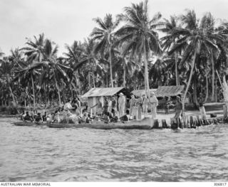 NEW GEORGIA, SOLOMON ISLANDS. 1943-03. NATIVE SCOUTS ABOUT TO SET OUT IN A CANOE WITH A UNITED STATES MARINE CORPS INTELLIGENCE PATROL FROM THE COASTWATCHERS STATION AT SEGI (ZFJ5) FAREWELLING THE ..