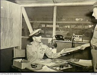 TOROKINA, BOUGAINVILLE ISLAND, SOLOMON ISLANDS. 1945-08-27. GROUP CAPTAIN (GP CAPT) DIXIE ROBISON CHAPMAN OF ADELAIDE, SA, IN COMMAND OF THE RAAF UNITS, SEATED AT HIS DESK IN HIS JUNGLE ..