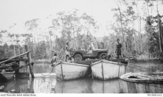 Oro Bay, New Guinea. 1943. The 83rd Anti-Aircraft Searchlight Battery Commander's jeep crossing Emo Creek on pontoons. New Guinea natives are assisting the crossing