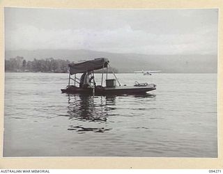 KALUMALAGI RIVER, JACQUINOT BAY, NEW BRITAIN, 1945-07-23. CFN L. JAMES (1) AND PTE F. FREEMAN (2), MEMBERS OF 1 INFANTRY TROOPS WORKSHOP ON A HOME MADE SURF SKI WHICH IS EQUIPPED WITH CANOPY TO ..