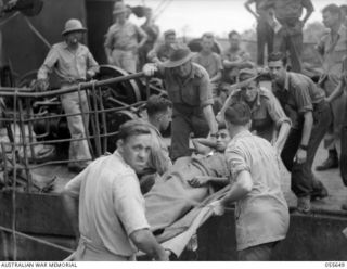 NEW GUINEA. 1943-07-28. WOUNDED MEMBERS OF THE 1ST PAPUAN INFANTRY BATTALION BROUGHT TO ORO BAY BY THE TUNGSIN. STRETCHER BEARERS ARE, LEFT TO RIGHT:- LANCE CORPORAL R. MCKIM; DRIVER K. FLINTOFT; ..
