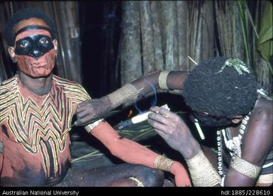 Preparing a dancer for his performance of a curing dance for a sick member of the community