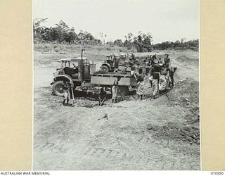 WAU - LAE ROAD, NEW GUINEA, 1944-03-10. AUSTRALIAN NEW GUINEA ADMINISTRATIVE UNIT NATIVES LOADING GRAVEL FROM THE BANKS OF THE MARKHAM RIVER 86.5 MILES FROM WAU INTO TIP TRUCKS FOR USE ON SURFACING ..