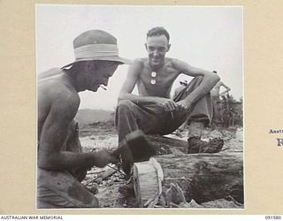 WIDE BAY, NEW BRITAIN, 1945-05-02. SAPPER H.C. LEE (1), TYING PILES. HE IS WATCHED BY SAPPER A.R. HORN (2). THE MEN, MEMBERS OF 13 FIELD COMPANY, ROYAL AUSTRALIAN ENGINEERS, ARE WORKING ON THE ..