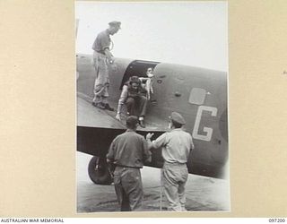 BORAM AIRSTRIP, WEWAK AREA, NEW GUINEA. 1945-09-28. MISS A. LEE, A MEMBER OF THE DARYA COLLIN BALLET TROUPE, BEING HELPED DOWN FROM A BEAUFORT BOMBER WHICH FLEW HER FROM AITAPE TO HEADQUARTERS 6 ..