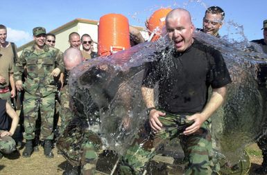 After getting their heads shaved, US Air Force (USAF) Captain (CAPT) L.D. Buerger, right and Lieutenant (LT) Ken King, with the 7th Expeditionary Maintenance Group (EMXG), are drenched with ice water at Andersen Air Force Base (AFB), Guam