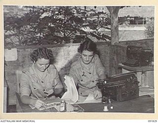 LAE, NEW GUINEA. 1945-05-15. CORPORAL G. MCCULKIN (1), AND PRIVATE D. CHAPLYN (2), WORKING AT THEIR NEW JOBS IN THE CAMP COMMANDANT'S OFFICE, HEADQUARTERS LAE BASE SUB AREA. A FEW DAYS AFTER THEIR ..